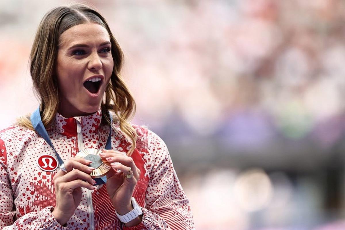 Bronze medallist Canada's Alysha Newman celebrates on the podium during the victory ceremony for the women's pole vault final athletics event at the Paris 2024 Olympic Games at Stade de France in Saint-Denis, north of Paris, on August 8, 2024.  Anne-Christine POUJOULAT / AFP