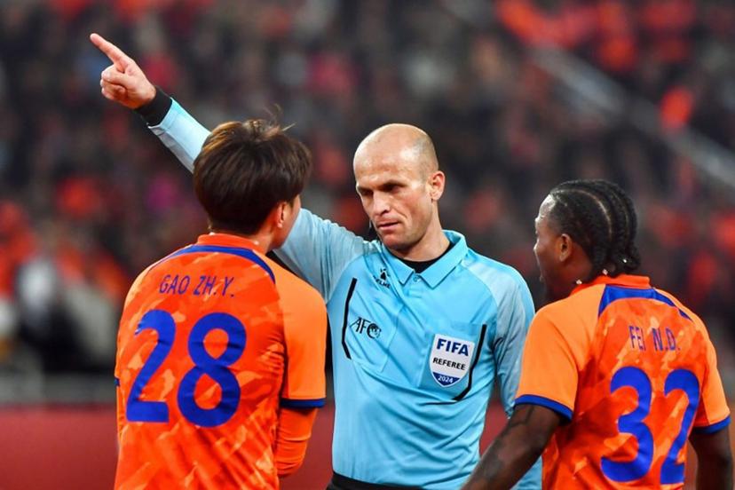 Shandong Taishan's Gao Zhunyi (L) receives a warning from referee Adham Mohammad Makhadmeh during the AFC Champions League quarterfinal match between Japan's Yokohama F Marinos and China's Shandong Taishan in Jinan, in China's eastern Shandong province on March 6, 2024.  STR / AFP