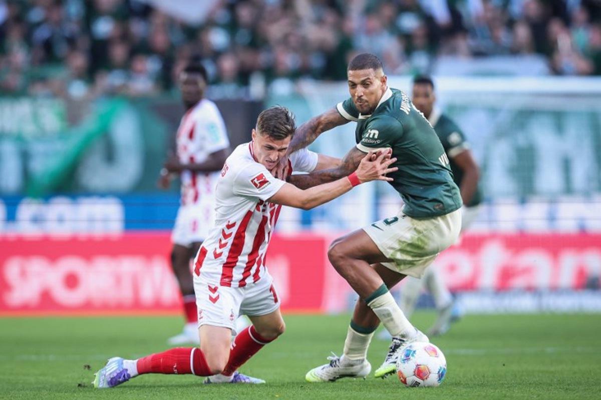 Wolfsburg's Brazilian midfielder #05 Vinicius Souza (R) and FC Cologne's Belgian-Spanish midfielder #17 Alessio Castro-Montes vie for the ball during the German first division Bundesliga football match between VfL Wolfsburg and FC Cologne in Wolfsburg, northern Germany, on September 13, 2025.  Ronny Hartmann / AFP