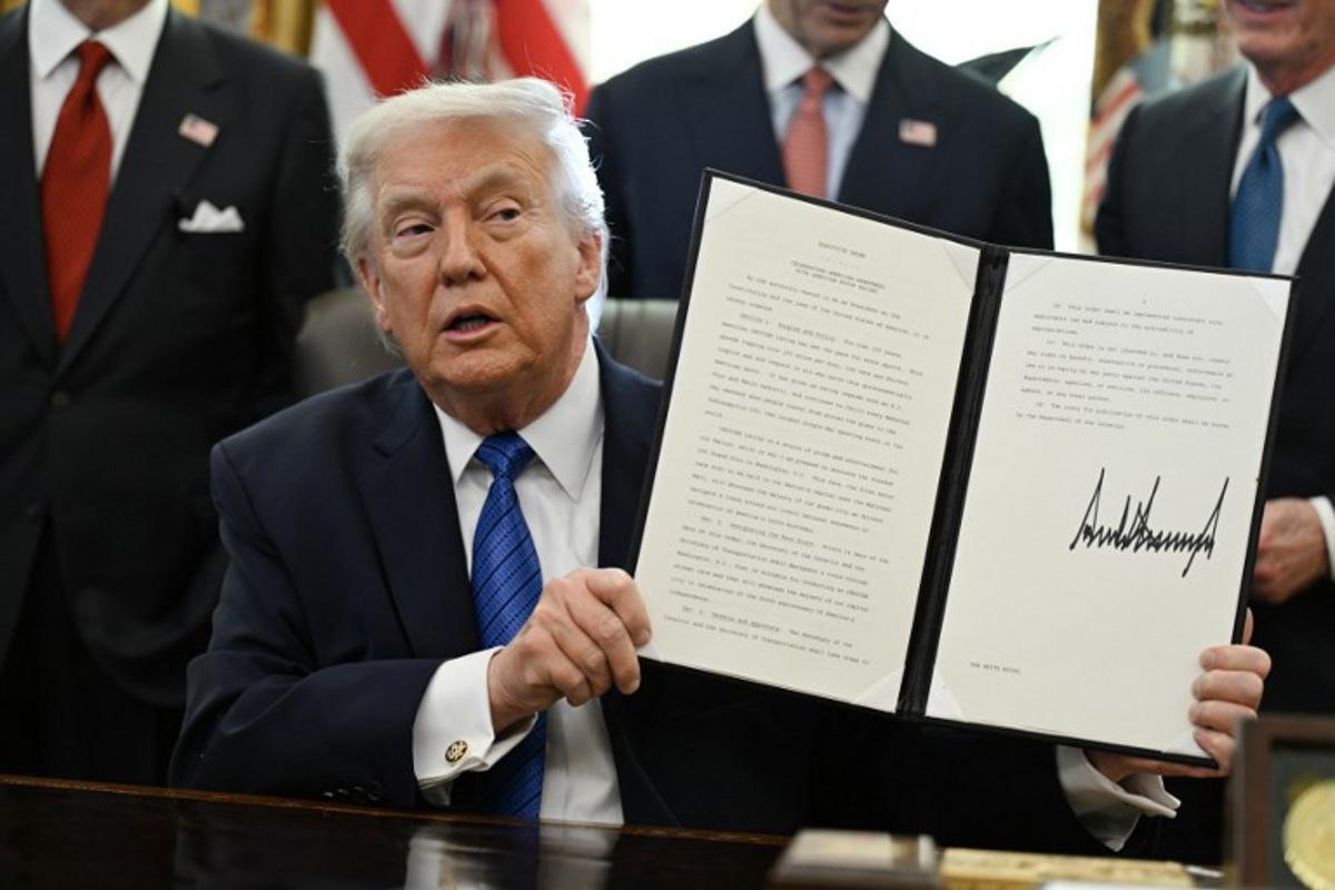 US President Donald Trump holds up a signed executive order in the Oval Office in the White House in Washington, DC, on January 30, 2026.  ANNABELLE GORDON / AFP
