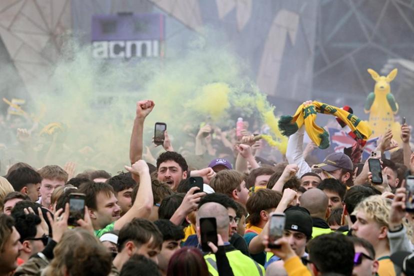 Football fans celebrate Australia's goal as they watch a broadcast of the FIFA World Cup 2026 Group D match between Australia and Turkey on a giant screen during a public viewing event in Melbourne on June 14, 2026.   WILLIAM WEST / AFP