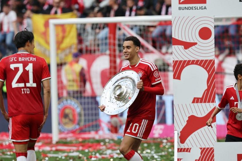 Bayern Munich's German midfielder #10 Jamal Musiala celebrates with the Bundesliga trophy near Bayern Munich's Japanese defender #21 Hiroki Ito after the German first division Bundesliga football match between FC Bayern Munich and FC Cologne in Munich, southern Germany, on May 16, 2026.  Alexandra BEIER / AFP