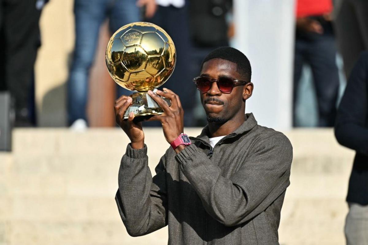 Paris Saint-Germain's French forward and 2025 Ballon d'Or winner Ousmane Dembele displays his trophy during a presentation ceremony at the City Hall in Evreux, his hometown and where he started playing club football, on October 12, 2025.  LOU BENOIST / AFP