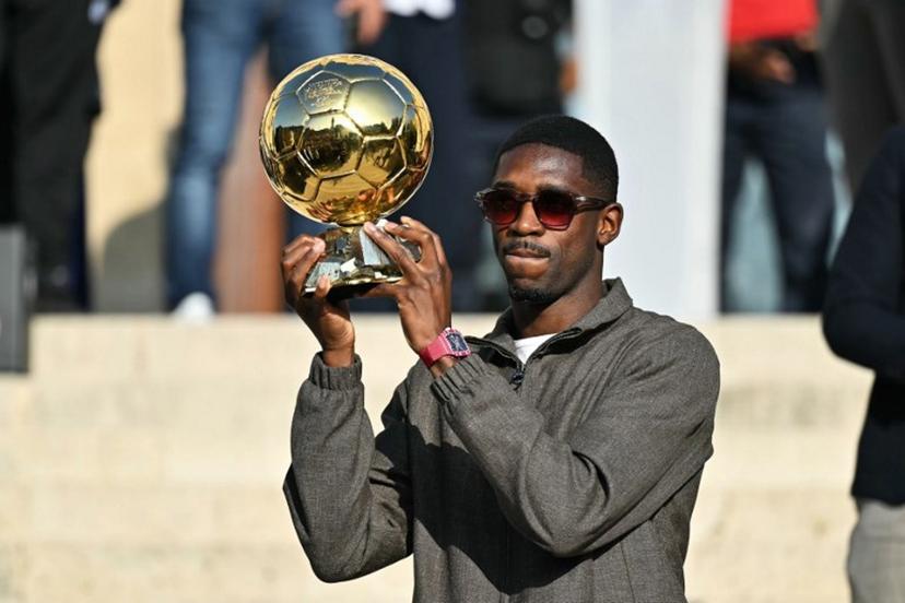 Paris Saint-Germain's French forward and 2025 Ballon d'Or winner Ousmane Dembele displays his trophy during a presentation ceremony at the City Hall in Evreux, his hometown and where he started playing club football, on October 12, 2025.  LOU BENOIST / AFP