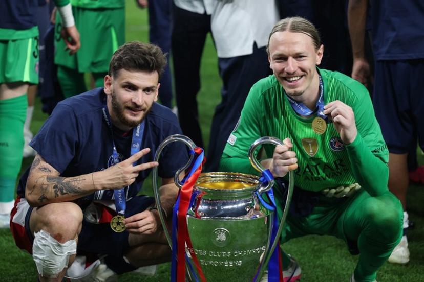 Paris Saint-Germain's Georgian forward #07 Khvicha Kvaratskhelia (L) and Paris Saint-Germain's Russian goalkeeper #39 Matvey Safonov pose with the trophy after winning the UEFA Champions League final football match between Paris Saint-Germain (PSG) and Arsenal FC at the Puskas Arena in Budapest on May 30, 2026.   FRANCK FIFE / AFP