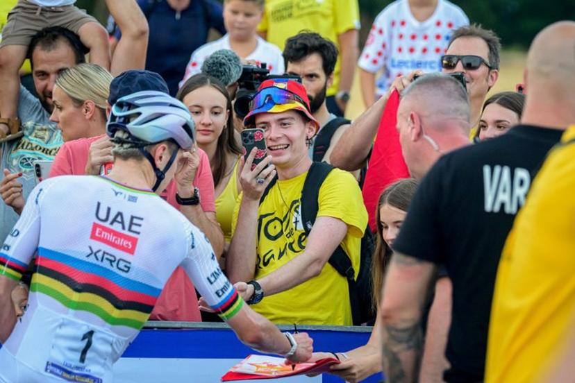Tour de France's five-time winner Slovenian rider Tadej Pogacar (L) signs autographs as supporters take photograph ahead of the start of the Tadej Pogacar's Criterium Elite Men's race in his hometown in Komenda, Slovenia on July 31, 2026.  Jure Makovec / AFP