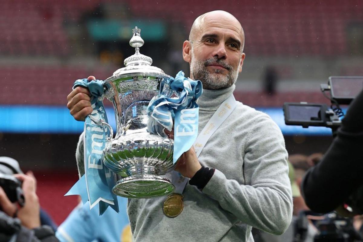 Manchester City's Spanish manager Pep Guardiola poses with the trophy on the pitch after the English FA Cup final football match between Chelsea and Manchester City at Wembley stadium in London, on May 16, 2026. Manchester City won the game 1-0. The third FA Cup success of Guardiola's reign ended City's run of two successive defeats in the final. Adrian Dennis / AFP