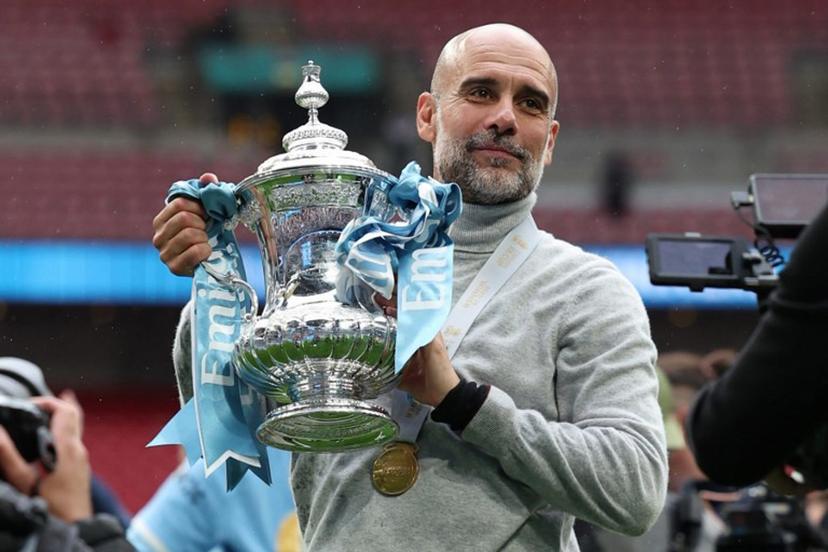 Manchester City's Spanish manager Pep Guardiola poses with the trophy on the pitch after the English FA Cup final football match between Chelsea and Manchester City at Wembley stadium in London, on May 16, 2026. Manchester City won the game 1-0. The third FA Cup success of Guardiola's reign ended City's run of two successive defeats in the final. Adrian Dennis / AFP