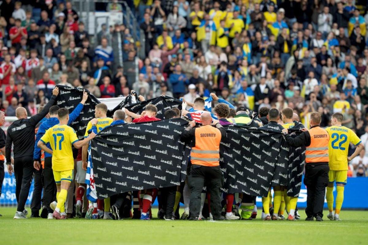 Denmark's and Ukraine's players huddle to accompany Denmark's midfielder #10 Christian Eriksen to a waiting ambulance during the football international friendly match between Denmark and Ukraine at Odense Stadium in Denmark, on June 7, 2026. Christian Eriksen collapsed during Denmark's friendly against Ukraine on June 7, 2026, five years after he suffered a cardiac arrest during the European Championships. Bo Amstrup / Ritzau Scanpix / AFP