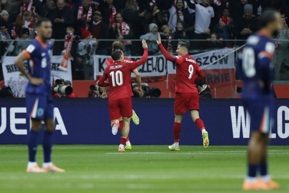 Poland's midfielder #10 Piotr Zielinski (C-L) and Poland's forward #09 Robert Lewandowski (C-R) celebrate after their team scored the opening 1-0 goal during the 1st round - day 9 - Group G World Cup 2026 European Qualifiers football match between Poland and the Netherlands on November 14, 2025 in Warsaw, Poland.  Wojtek RADWANSKI / AFP