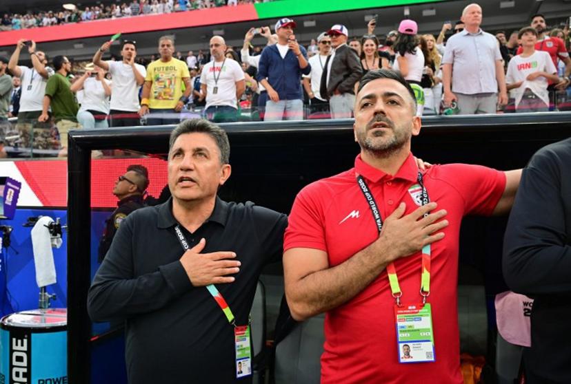 Iran's head coach Amir Ghalenoei (L) and assistant coach Saeed Alhoei (R) sing the national anthem ahead of the 2026 World Cup Group G football match between Iran and New Zealand at Los Angeles Stadium in Inglewood on June 15, 2026.   Frederic J. Brown / AFP