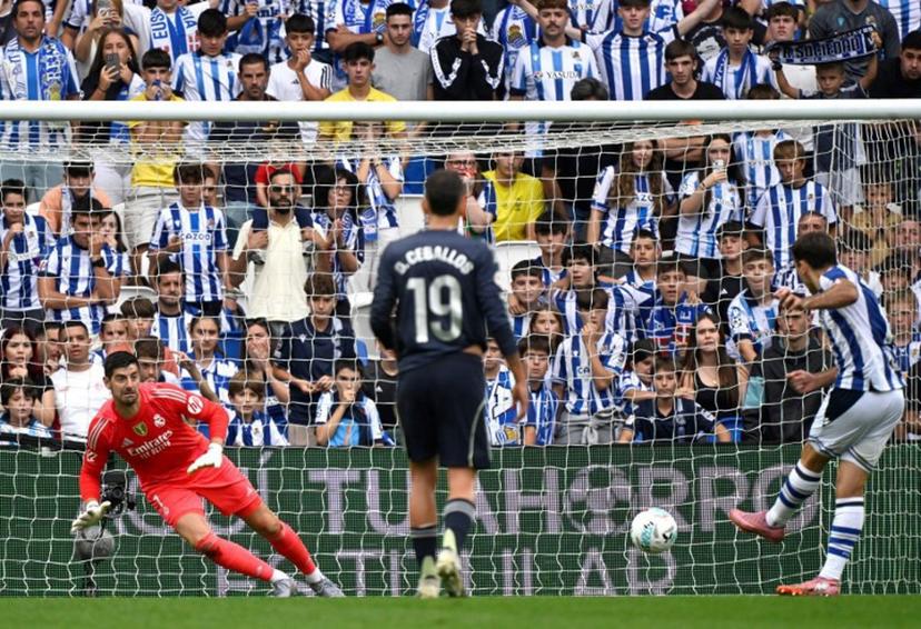 Real Sociedad's Spanish forward #10 Mikel Oiarzabal scores his team's first goal from the penalty spot in spite of Real Madrid's Belgian goalkeeper #01 Thibaut Courtois during the Spanish league football match between Real Sociedad and Real Madrid CF at Anoeta Stadium in San Sebastian on September 13, 2025.  ANDER GILLENEA / AFP