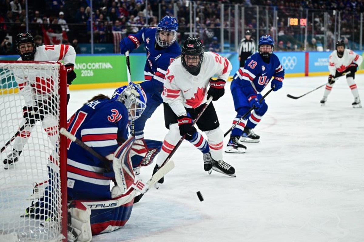 Canada's #24 Natalie Spooner (C) fights for the puck with USA's #05 Megan Keller (2nd L) and USA's #31 Aerin Frankel (L)  during the women's gold medal ice hockey match between USA and Canada at the Milano Santagiulia Ice Hockey Arena during the Milano Cortina 2026 Winter Olympic Games in Milan, on February 19, 2026.  JULIEN DE ROSA / AFP