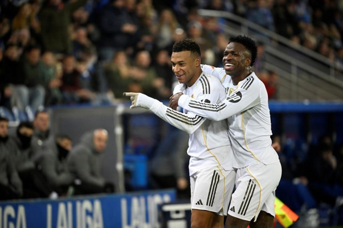 Real Madrid's French foward #10 Kylian Mbappe celebrates scoring his team's first goal with Real Madrid's Brazilian forward #07 Vinicius Junior during the Spanish league football match between Deportivo Alaves and Real Madrid CF at the Mendizorroza stadium in Vitoria on December 14, 2025.  ANDER GILLENEA / AFP