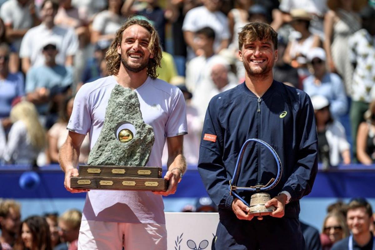 Greece's Stefanos Tsitsipas (L) poses with the trophy following his victory against Belgium's Raphael Collignon (R) during their men's singles final match at the Swiss Open tennis tournament in Gstaad, on July 19, 2026.  Fabrice COFFRINI / AFP