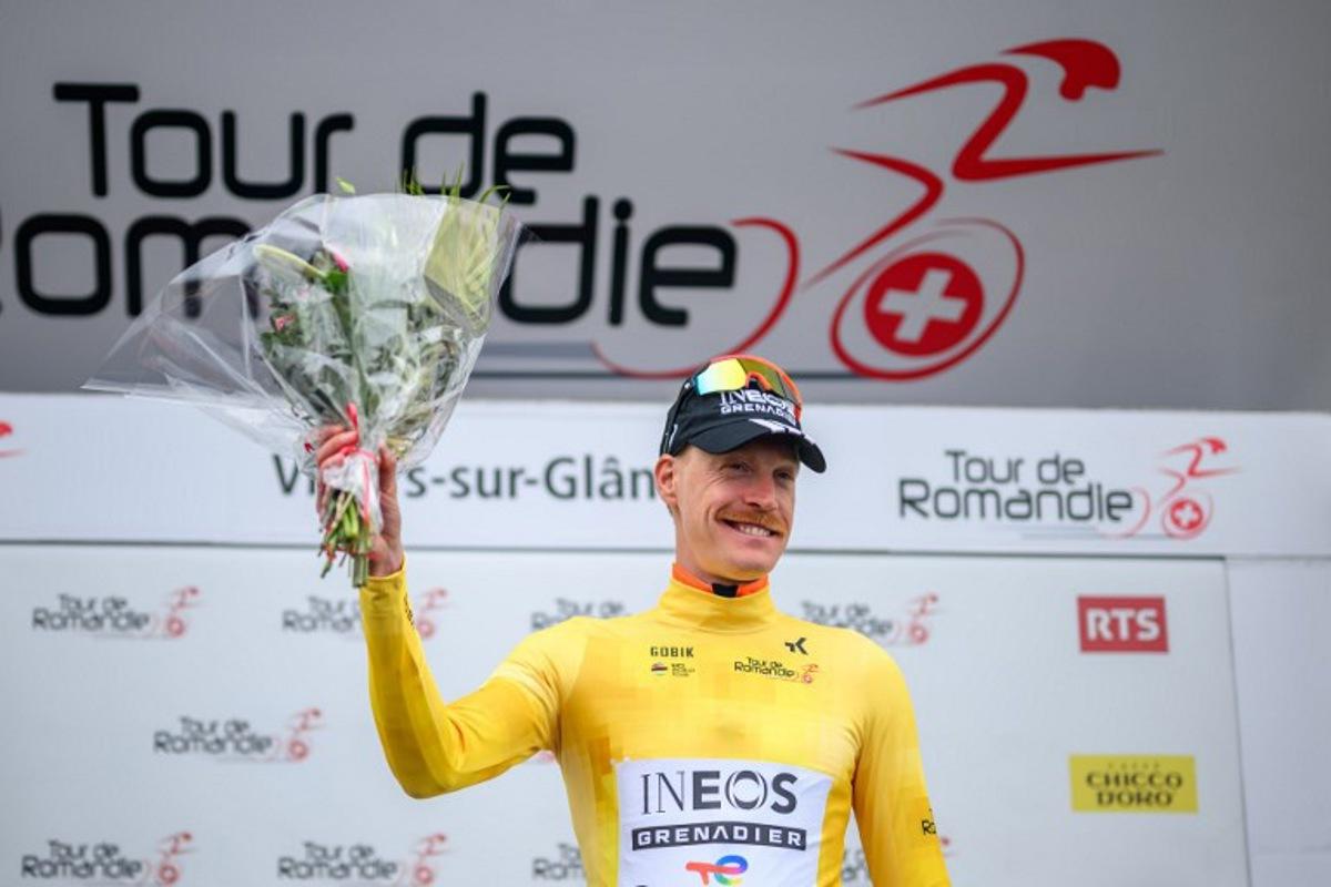 INEOS Grenadiers' French rider Dorian Godon wearing the overall leader's yellow jersey celebrates on the podium after winning the prologue of the Tour of Romandie UCI cycling World tour, a 3.2 km time trial from Villars-sur-Glane to Villars-sur-Glane on April 28, 2026.  Fabrice COFFRINI / AFP