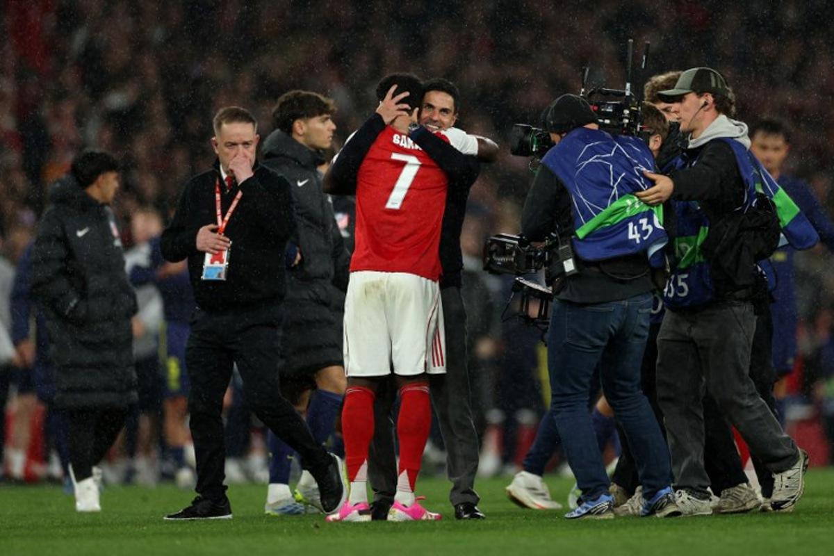 Arsenal's Spanish manager Mikel Arteta hugs Arsenal's English midfielder #07 Bukayo Saka after winning the UEFA Champions League second-leg semi-final football match between Arsenal and Atletico Madrid at the Emirates Stadium in north London on May 5, 2026.  Adrian Dennis / AFP