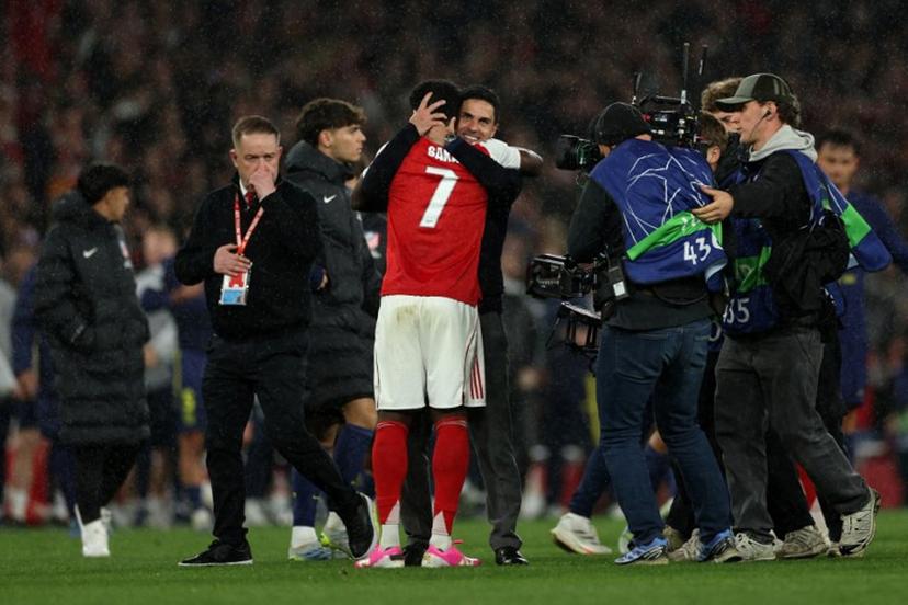 Arsenal's Spanish manager Mikel Arteta hugs Arsenal's English midfielder #07 Bukayo Saka after winning the UEFA Champions League second-leg semi-final football match between Arsenal and Atletico Madrid at the Emirates Stadium in north London on May 5, 2026.  Adrian Dennis / AFP