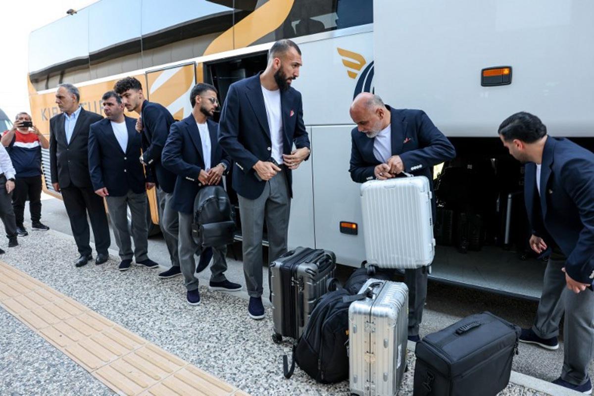 Iran's midfielder #15 Roozbeh Cheshmi (C) and Iran's midfielder #10 Mehdi Ghayedi (C-L) descend from a bus as the Iranian national football team arrives at Antalya Airport for their departure to Mexico ahead of the FIFA 2026 World Cup football tournament, in Antalya, on June 6, 2026.  Iran lashed out at the United States on June 6 for refusing visas to some of its World Cup squad support staff as the players were to leave Turkey for Mexico. ONER SAN / AFP
