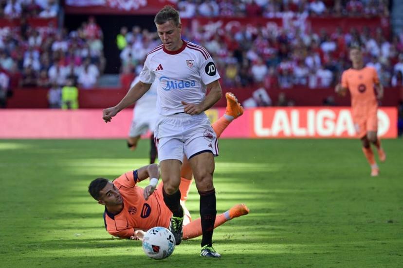 Sevilla's Spanish defender #03 Cesar Azpilicueta and Barcelona's Spanish forward #07 Ferran Torres (BOTTOM) fight for the ball during the Spanish league football match between Sevilla FC and FC Barcelona at Ramon Sanchez Pizjuan Stadium in Seville on October 5, 2025.  CRISTINA QUICLER / AFP