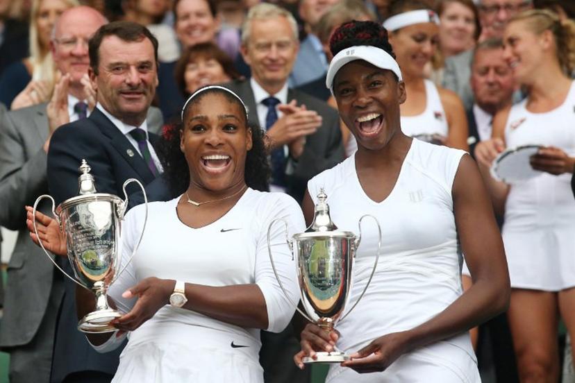 US player Serena Williams (L) and her partner US player Venus Williams (R) pose with the winner's trophies after beating Hungary's Timea Babos and Kazakhstan's Yaroslava Shvedova to win the women's doubles final on the thirteenth day of the 2016 Wimbledon Championships at The All England Lawn Tennis Club in Wimbledon, southwest London, on July 9, 2016.  JUSTIN TALLIS / AFP