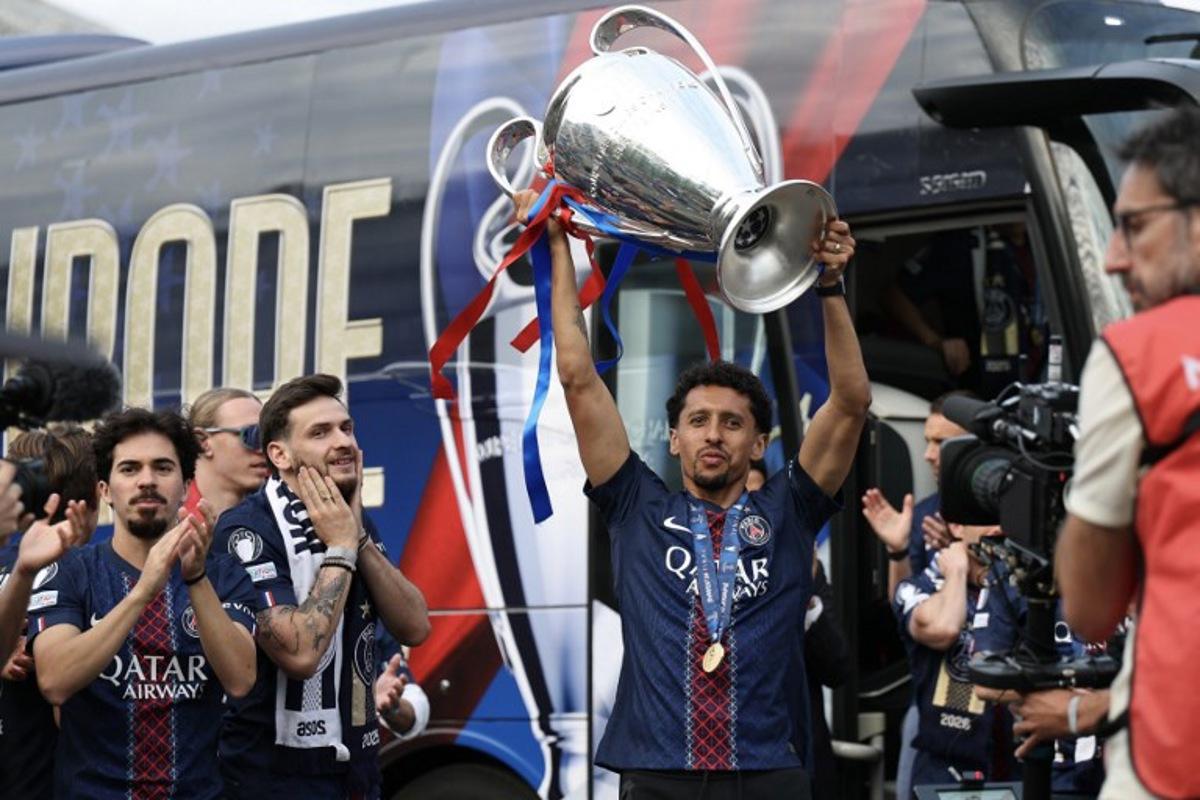 Paris Saint-Germain's Brazilian defender #05 Marquinhos celebrates next to Paris Saint-Germain's Portuguese midfielder #17 Vintinha (L) and Paris Saint-Germain's Georgian forward #07 Khvicha Kvaratskhelia (2L) with the UEFA Champions League trophy upon arriving at the Parc des Princes stadium, in Paris on May 31, 2026, during a special event organised to celebrate with supporters their victory over Arsenal FC in the UEFA Champions League final. Paris Saint-Germain (PSG) claimed back-to-back Champions League triumphs with a 4-3 shoot-out win over Arsenal following a 1-1 draw after extra time on May 30, 2026. FRANCK FIFE / AFP