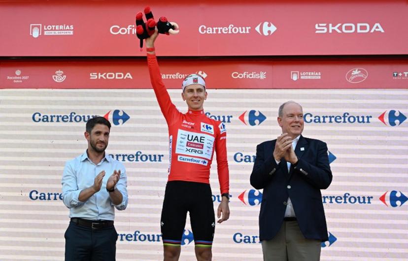 UAE Team Emirates - XRG team's Slovenian rider Tadej Pogacar celebrates on the podium wearing the overall leader's red jersey flanked by Prince's Albert II of Monaco (R) and Manosque's mayor Camille Galtier after the second stage of the Vuelta a Espana 2026, a 214,3 km race between Monaco and Manosque on August 23, 2026.  Miguel MEDINA / AFP