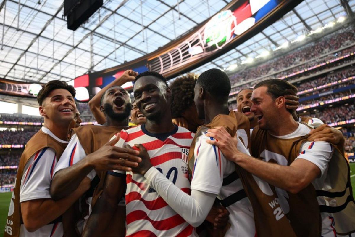 US forward #20 Folarin Balogun (c) celebrates with teammates after scoring his team's third goal during the 2026 World Cup Group D football match between USA and Paraguay at the Los Angeles Stadium in Inglewood on June 12, 2026.  Patrick T. Fallon / AFP