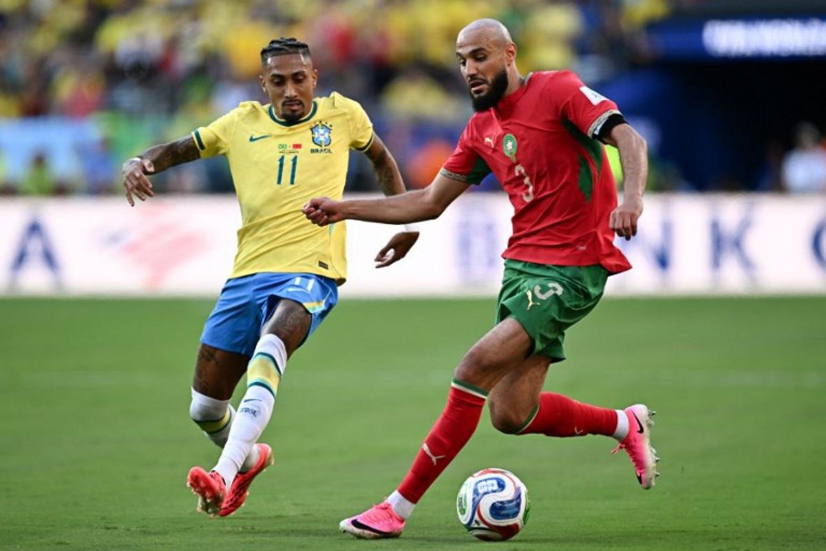Brazil's forward #11 Raphinha and Morocco's defender #03 Noussair Mazraoui fight for the ball during the 2026 World Cup Group C football match between Brazil and Morocco at the New York/New Jersey Stadium in East Rutherford on June 13, 2026.  Jewel SAMAD / AFP