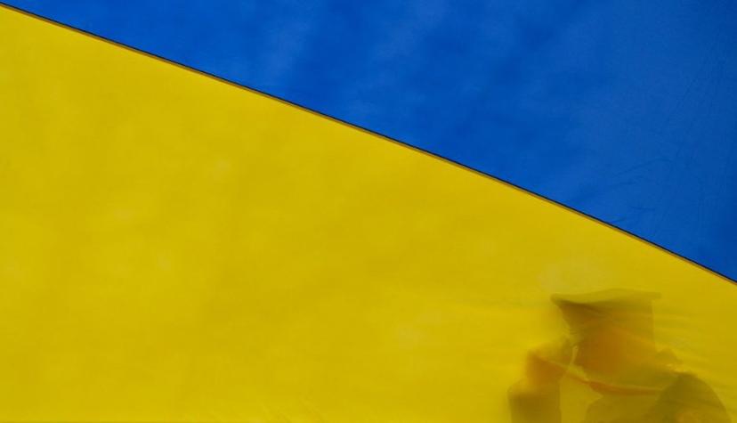 A Ukrainian serviceman sets his cap straigh as he participates in holding the national flag beore it raises to the flagpole during a ceremony marking the first anniversary of the retreat of Russian troops from the Ukrainian town of Bucha, in Bucha, near Kyiv, on March 31, 2023.   Sergei SUPINSKY / AFP