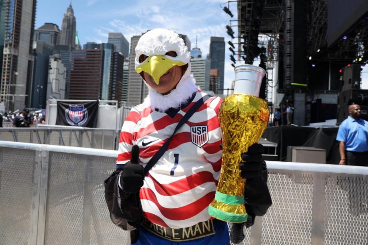 An attendee wearing an eagle mask poses holding an object made to resemble a FIFA World Cup trophy during the US Men's National Team 2026 World Cup roster announcement in New York, on May 26, 2026.  TIMOTHY A. CLARY / AFP