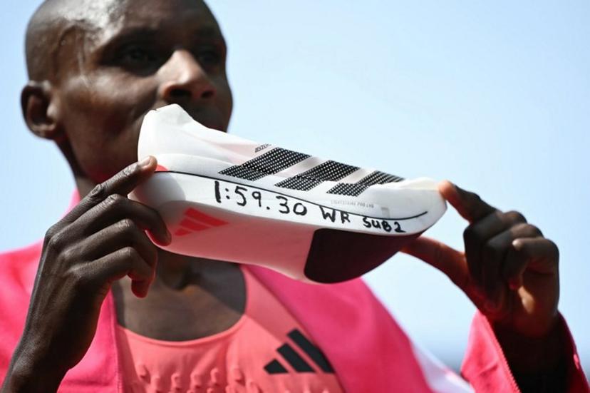 Kenya's Sabastian Sawe poses with his new world record time written on his running shoe at the finish of the 2026 London Marathon in central London on April 26, 2026. Kenya's Sabastian Sawe broke the two-hour mark for the first time in history on Sunday in winning the London Marathon. JUSTIN TALLIS / AFP