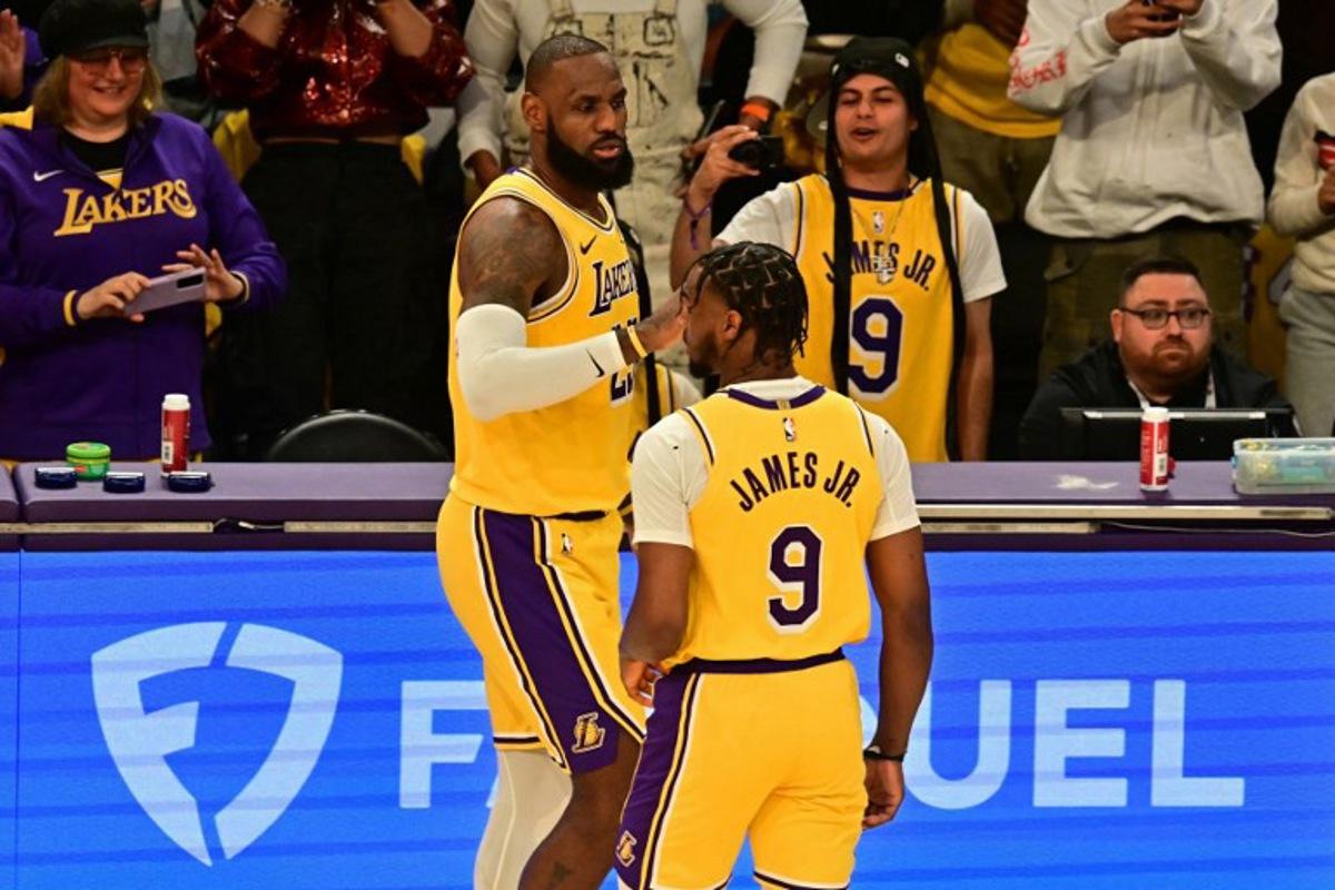 Los Angeles Lakers' US small forward #23 LeBron James (L) and Los Angeles Lakers' US guard #09 Bronny James are seen on court during the NBA game season opener between the Los Angeles Lakers and the Minnesota Timberwolves at Crypto Arena in Los Angeles on October 22, 2024. LeBron and Bronny are the first father and son to play together in any NBA game. Frederic J. Brown / AFP