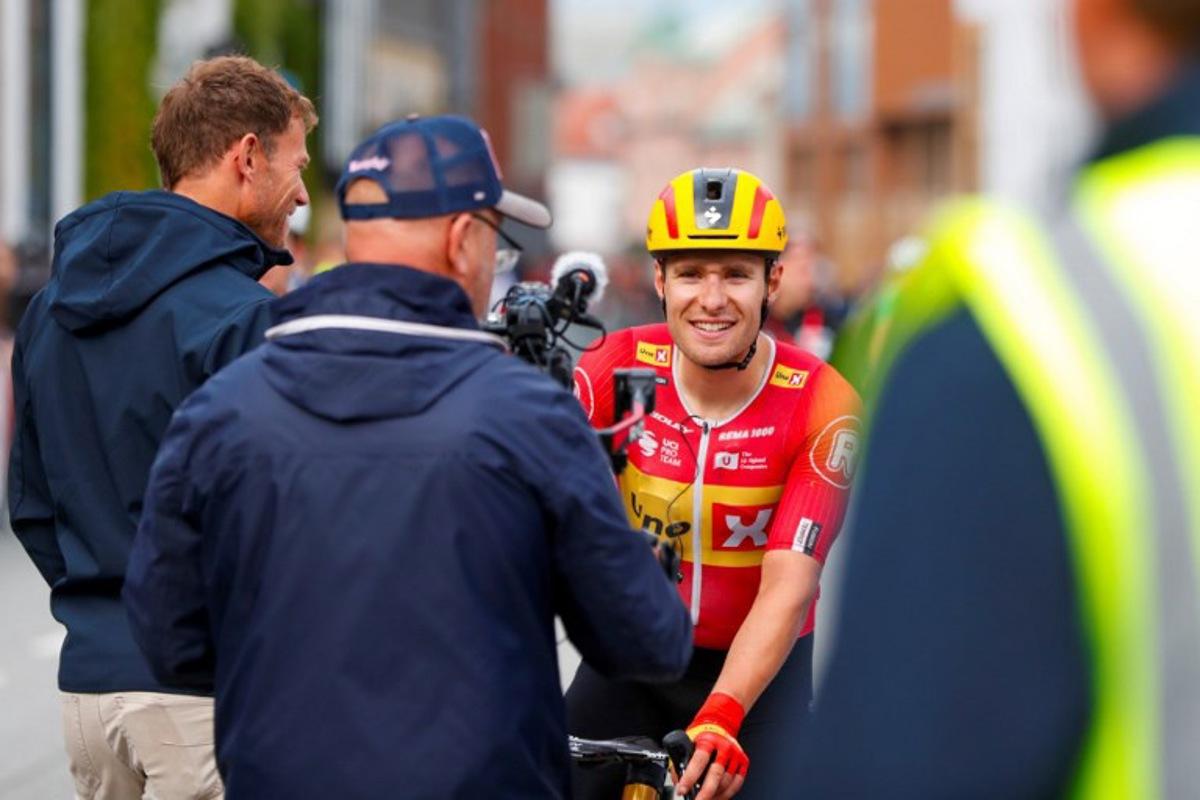 Uno-X Pro Cycling Team's Norwegian rider Fredrik Dversnes (R) reacts and is welcomed by Uno-X Mobility's CEO Thor Hushovd (L) after winning the fourth and final stage of the Arctic Cyling Race 2025 in Tromso, Norway, on August 10, 2025.  Rune Stoltz Bertinussen / NTB / AFP