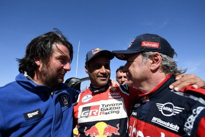 First-placed for the auto category JCW X-RAID Mini Team Spain's driver Carlos Sainz (R), celebrates as he is congratulated by second-placed Toyota's team Qatar's driver Nasser Al-Attiyah (C) and by diector of the Dakar 2020 David Castera (L) on the finish area in Qiddiya at the end of the stage 12 of the Dakar 2020 between Haradh and Qiddiya, Saudi Arabia, on January 17, 2020.  FRANCK FIFE / AFP