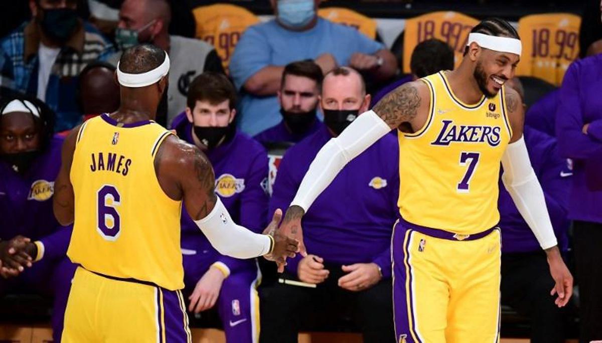 LeBron James and Carmelo Anthony of the Los Angeles Lakers touch hands in a break of action against the Golden State Warriors  during their NBA season opener in Los Angeles, California on October 19, 2021.  Frederic J. BROWN / AFP