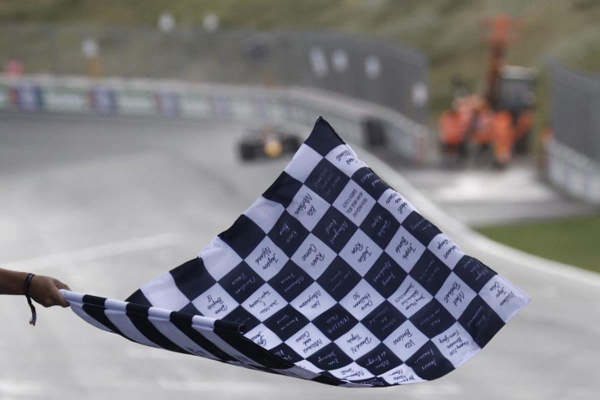 A person waves a finish flag as Red Bull Racing's Dutch driver Max Verstappen drives to win the Dutch Formula One Grand Prix race at The Circuit Zandvoort, in Zandvoort on August 27, 2023. SIMON WOHLFAHRT / POOL / AFP