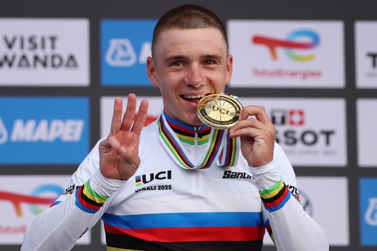 Gold medallist Belgian rider Remco Evenepoel bites his medal on the podium following the men's Elite Individual Time Trial cycling event during the UCI 2025 Road World Championships, in Kigali, on September 21, 2025. Anne-Christine POUJOULAT / AFP
