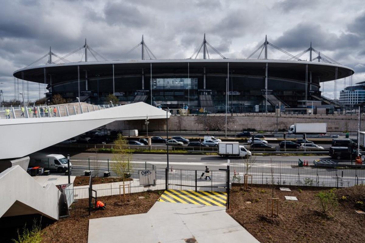 This photograph taken on March 28, 2024 shows a view of the footbridge connecting the 'Stade de France' stadium with the Aquatics Centre built for the Paris 2024 Olympic Games to be used for artistic swimming, diving and water polo competitions in Saint Denis, near Paris. VenhoevenCS & Ateliers 2/3/4/ designed the building. The Seine-Saint-Denis department north of Paris will host a number of events for the Paris 2024 Olympic and Paralympic Games, with venues including the Stade de France and Aquatics Centre, as well as the Olympic Village. Dimitar DILKOFF / AFP