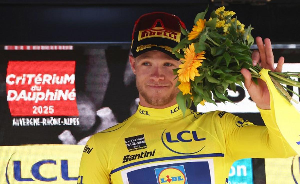 Lidl-Trek's Italian rider Jonathan Milan wearing the overall leader's yellow jersey celebrates on the podium of the 2nd stage of the 77th edition of the Criterium du Dauphine cycling race, 204,6 km between Prémilhat and Issoire, on June 9, 2025. Anne-Christine POUJOULAT / AFP