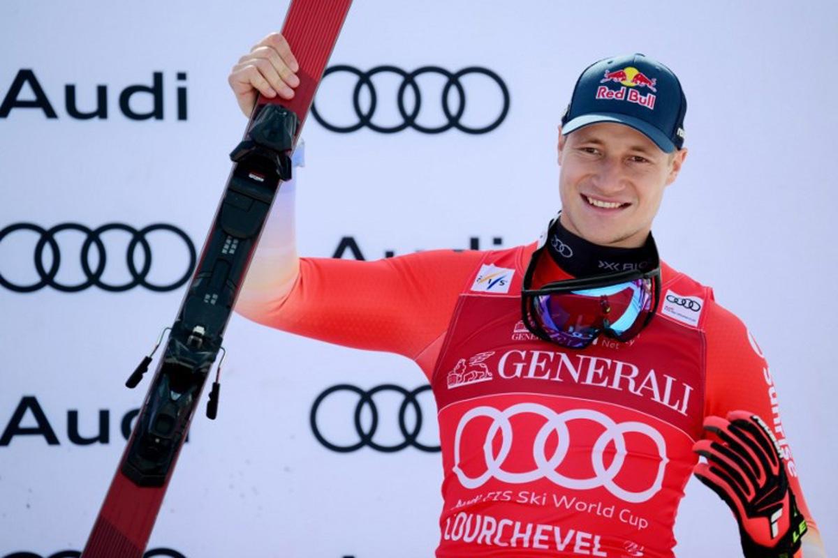 Third placed Switzerland's Marco Odermatt celebrates on the podium after the Men's Downhill event of the FIS Alpine World Cup in Courchevel, French Alps, on March 13, 2026. Olivier CHASSIGNOLE / AFP