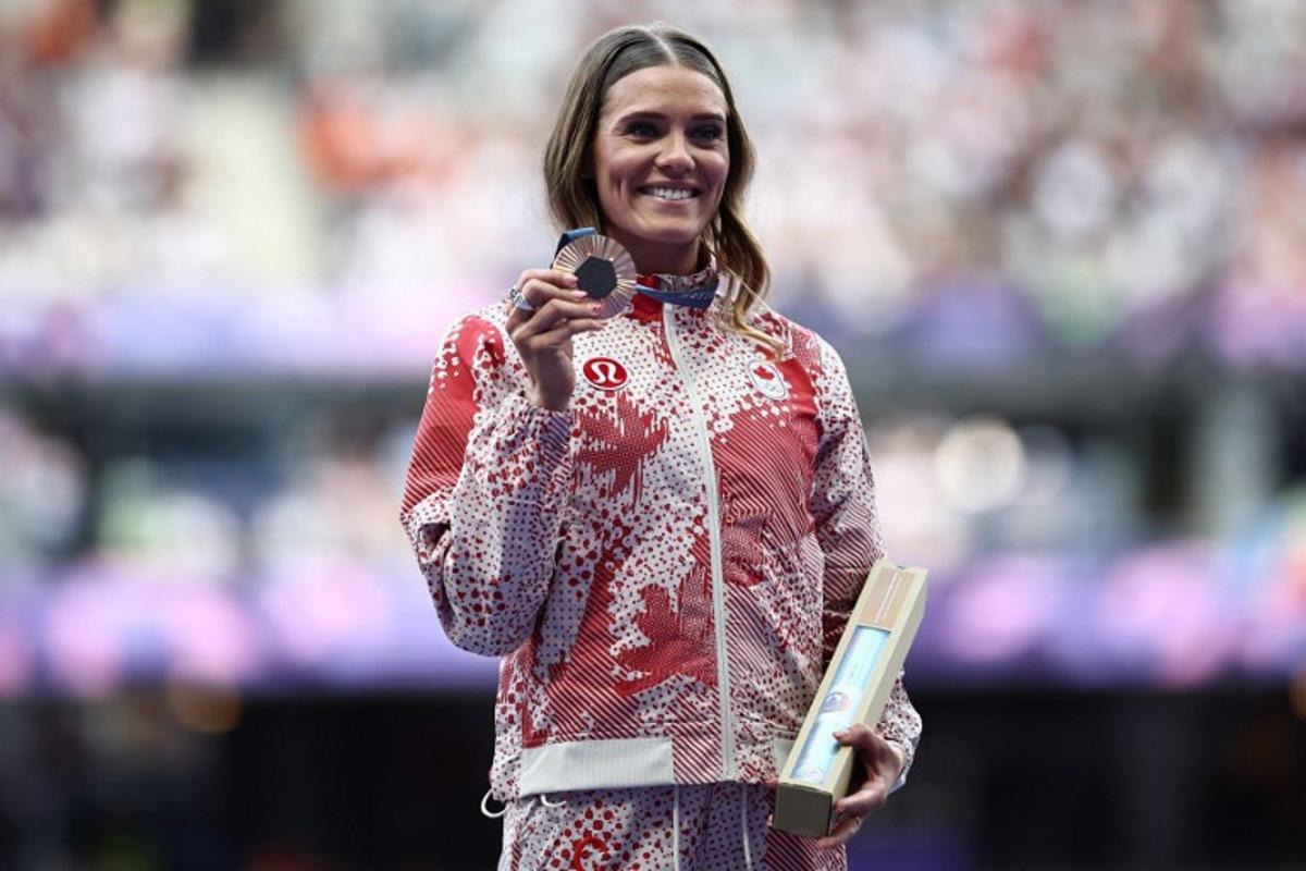 Bronze medallist Canada's Alysha Newman celebrates on the podium during the victory ceremony for the women's pole vault final athletics event at the Paris 2024 Olympic Games at Stade de France in Saint-Denis, north of Paris, on August 8, 2024. Anne-Christine POUJOULAT / AFP