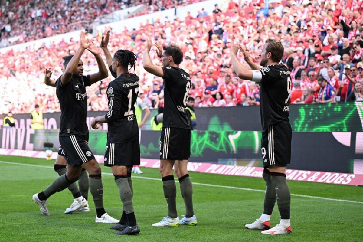 Bayern Munich's English forward #09 Harry Kane celebrates with team mates after scoring his team's fourth goal 3:4 during the German first division Bundesliga football match between 1 FSV Mainz 05 and FC Bayern Munich in Mainz, western Germany on April 25, 2026. Kirill KUDRYAVTSEV / AFP