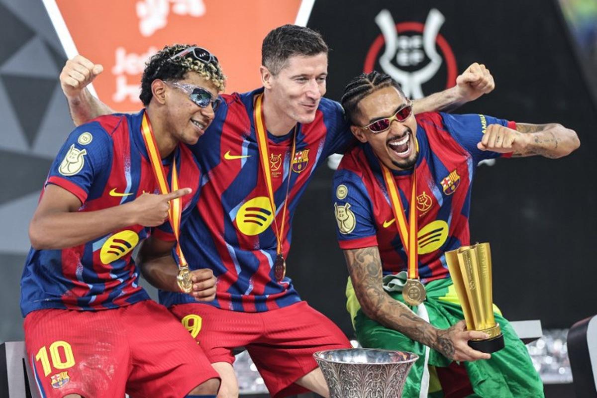 Barcelona's Spanish forward #10 Lamine Yamal, Polish forward #09 Robert Lewandowski and Brazilian forward #11 Raphinha celebrate after winning the Spanish Super Cup final football match between FC Barcelona and Real Madrid at the King Abdullah Stadium in Jeddah on January 11, 2026. Fadel SENNA / AFP