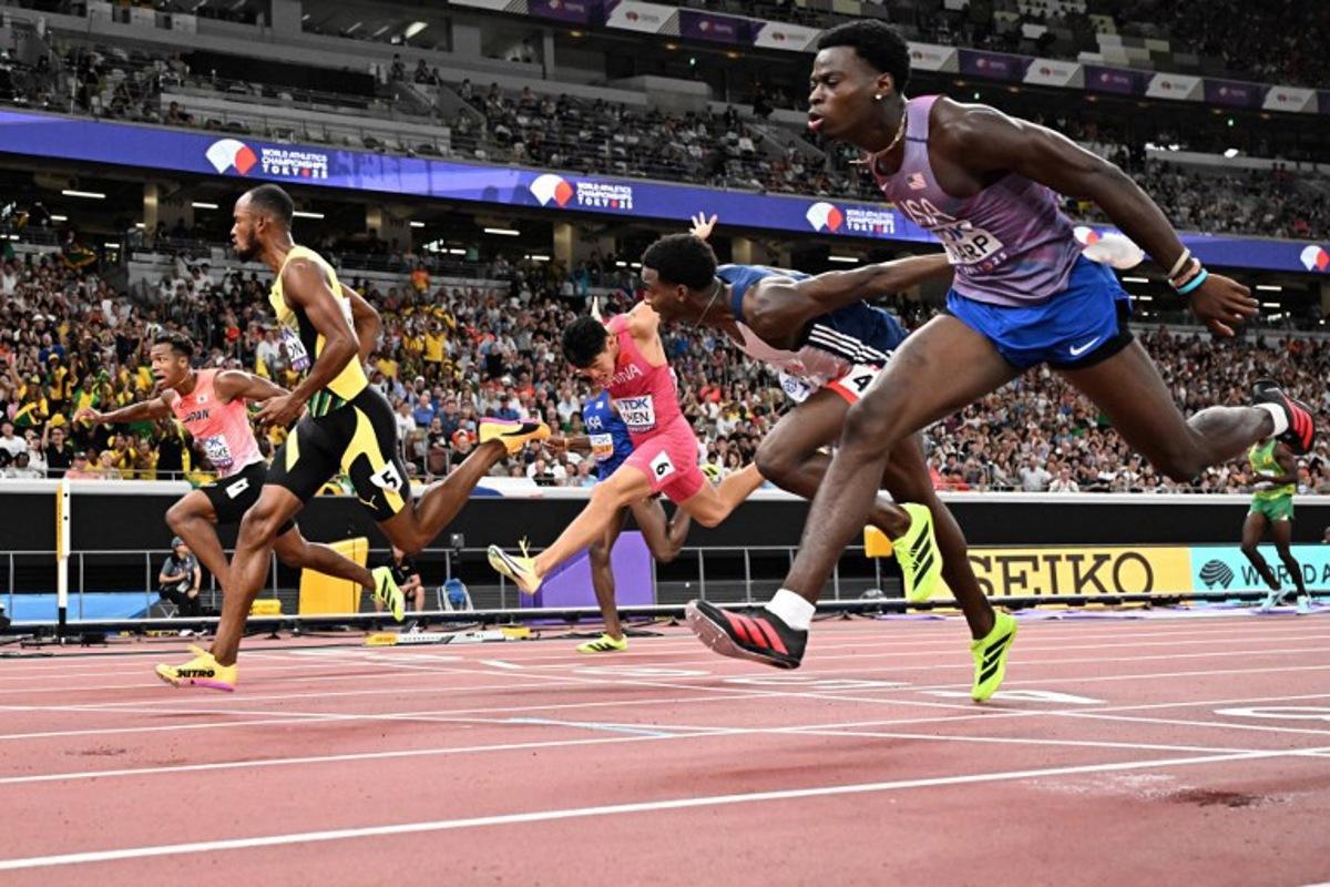 Athletes including US' athlete Ja'Kobe Tharp (R) and Jamaica's athlete Orlando Bennett (2nd L) cross the finish line in the men's 110m hurdles heats during the World Athletics Championships in Tokyo on September 15, 2025. Jewel SAMAD / AFP