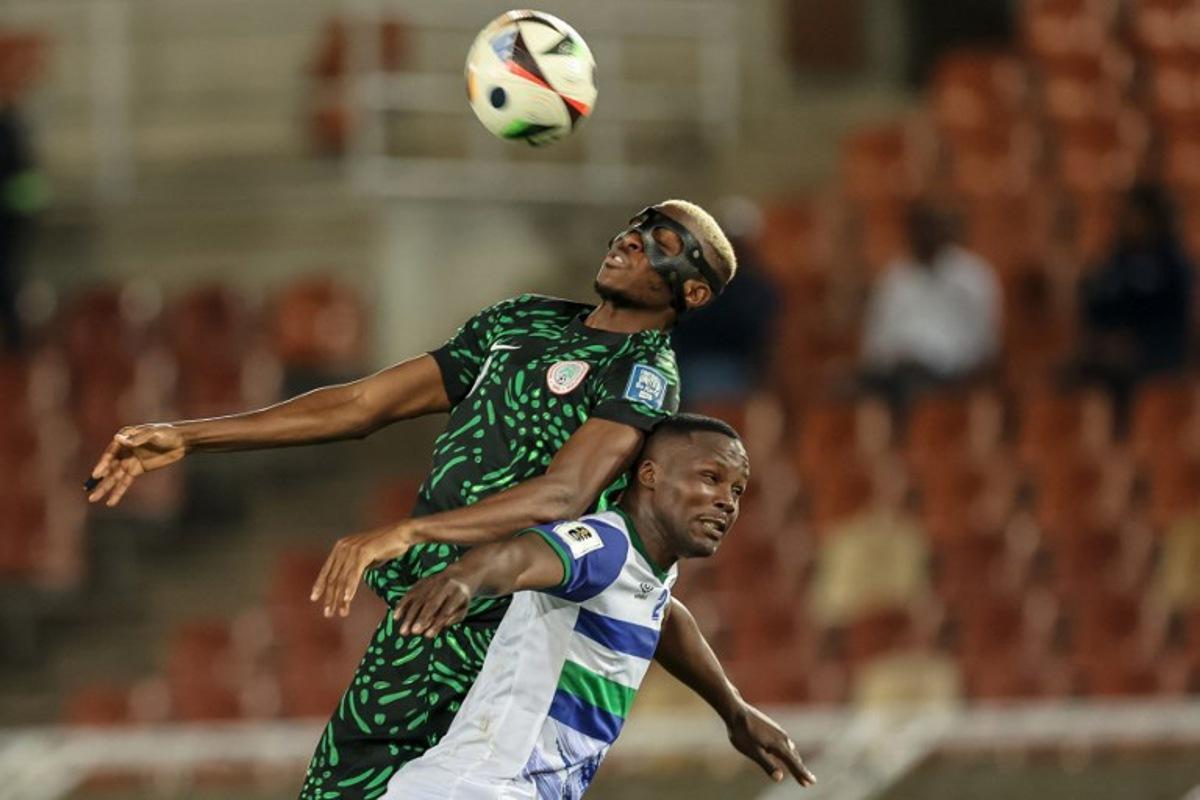 Nigeria's forward #9 Victor Osimhen jumps to head the ball as he is challenged by Lesotho's defender #2 Motlomelo Mkhwanazi during the FIFA World Cup 2026 Africa qualifiers group C match between Lesotho and Nigeria at the Peter Mokaba Stadium in Polokwane on October 10, 2025. PHILL MAGAKOE / AFP