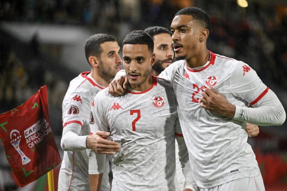 Tunisia's forward #07 Elias Achouri is congratulated by Tunisia's midfielder #17 Ellyes Skhiri, Tunisia's defender #06 Dylan Bronn and Tunisia's defender #20 Yan Valery during the Africa Cup of Nations (CAN) Group C football match between Tunisia and Uganda at Rabat Olympic Stadium in Rabat on December 23, 2025. SEBASTIEN BOZON / AFP
