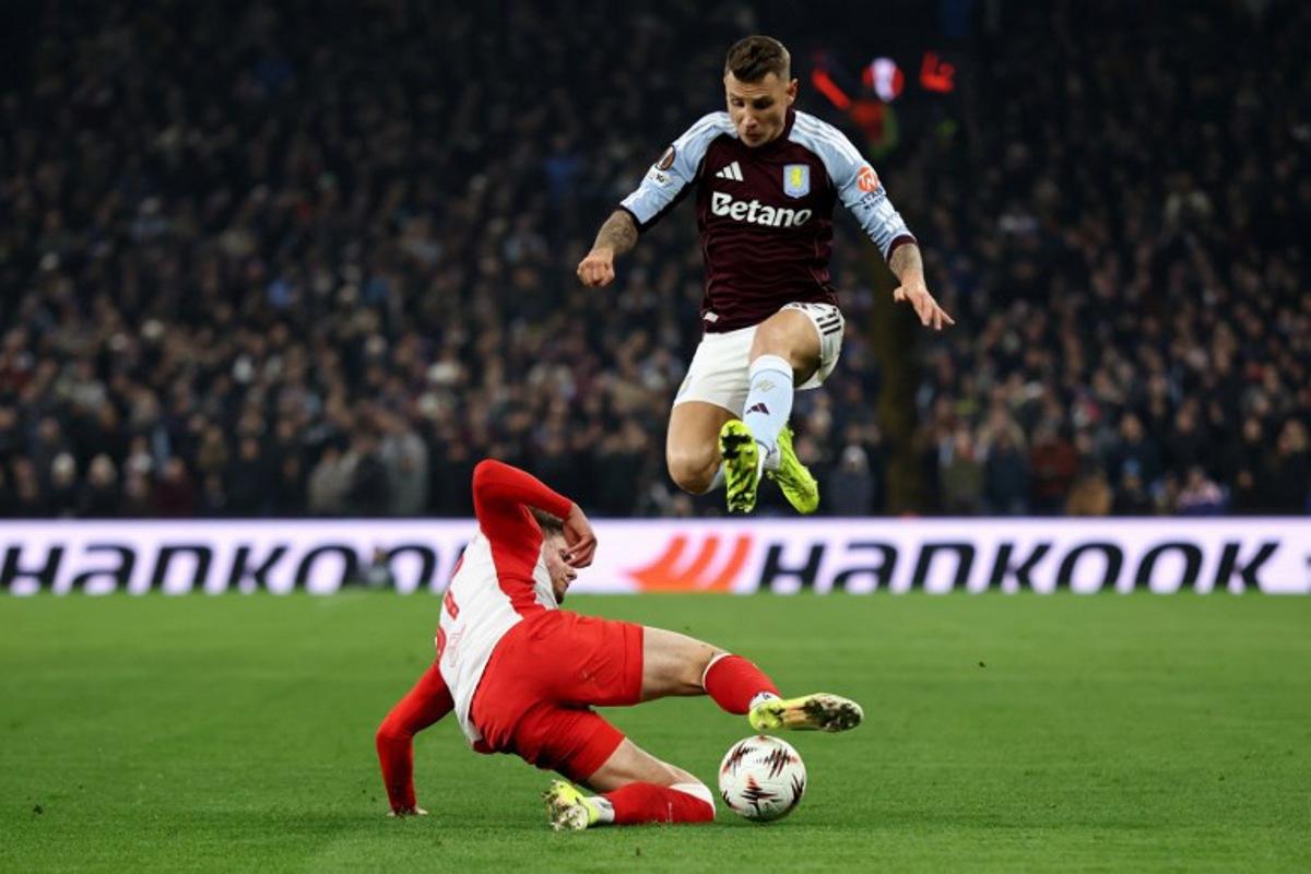 Aston Villa's French defender #12 Lucas Digne jumps over a tackle from Salzburg's Austrian midfielder #37 Tim Trummer during the UEFA Europa League league-stage football match between Aston Villa and RB Salzburg at Villa Park in Birmingham, central England on January 29, 2026. Darren Staples / AFP