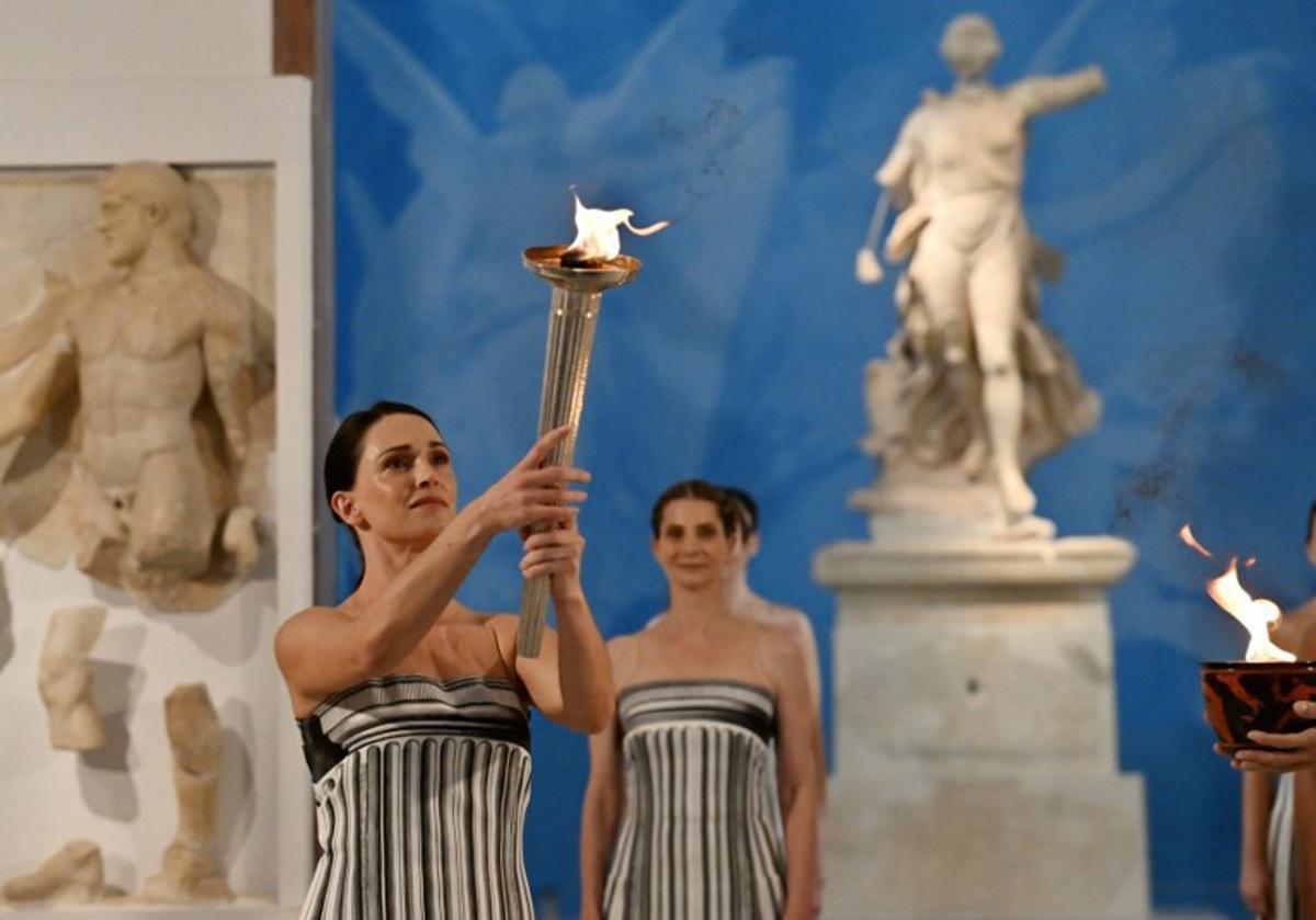 Greek actress Mary Mina (L), playing the role of the High Priestess, takes part in the flame lighting ceremony of the Olympic flame, for the Olympic Winter Games Milano Cortina 2026, at the Museum of ancient Olympia, in Olympia on November 26, 2025. Aris MESSINIS / AFP