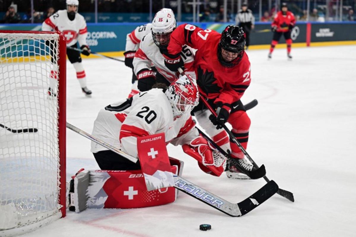 Switzerland's goalkeeper #20 Andrea Braendli (L) makes a save during the women's play-off semi-final ice hockey match between Canada and Switzerland at the Milano Santagiulia Ice Hockey Arena during the Milano Cortina 2026 Winter Olympic Games in Milan, on February 16, 2026. Piero CRUCIATTI / AFP